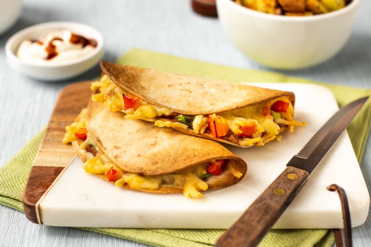 Cheesy vegetarian quesadillas on a white board.