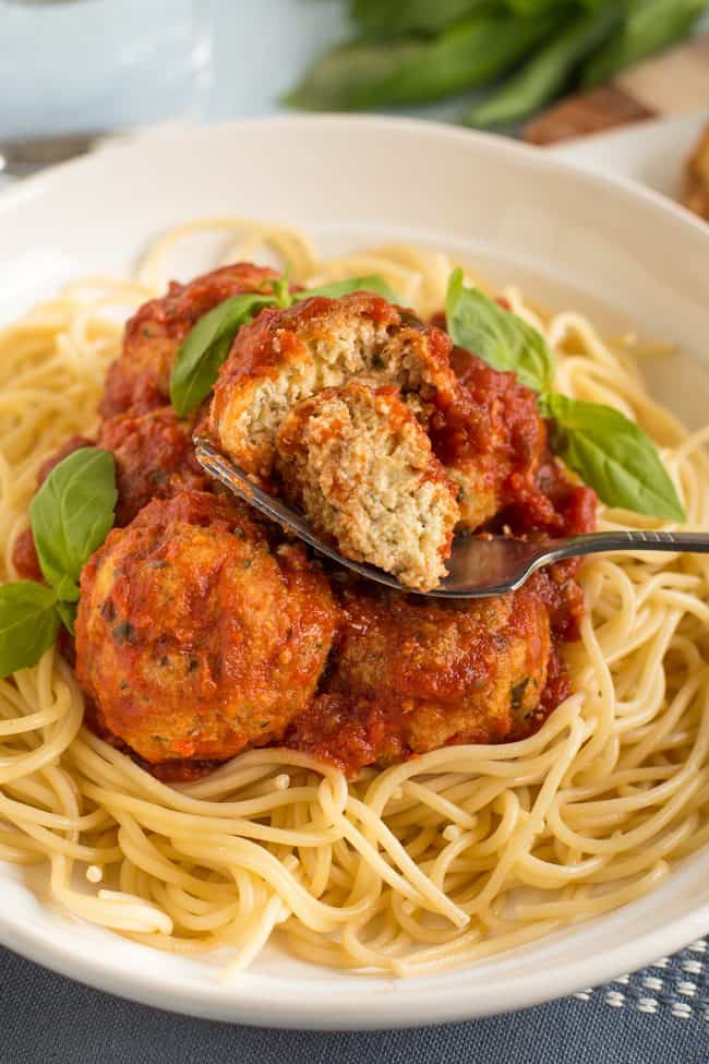 Cheesy tofu meatballs in a bowl, with one cut in half with a fork