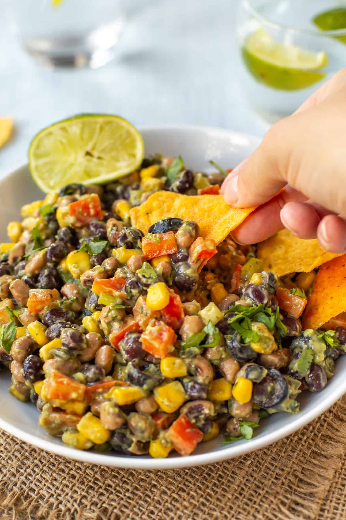 A hand taking a scoop of creamy avocado cowboy caviar.