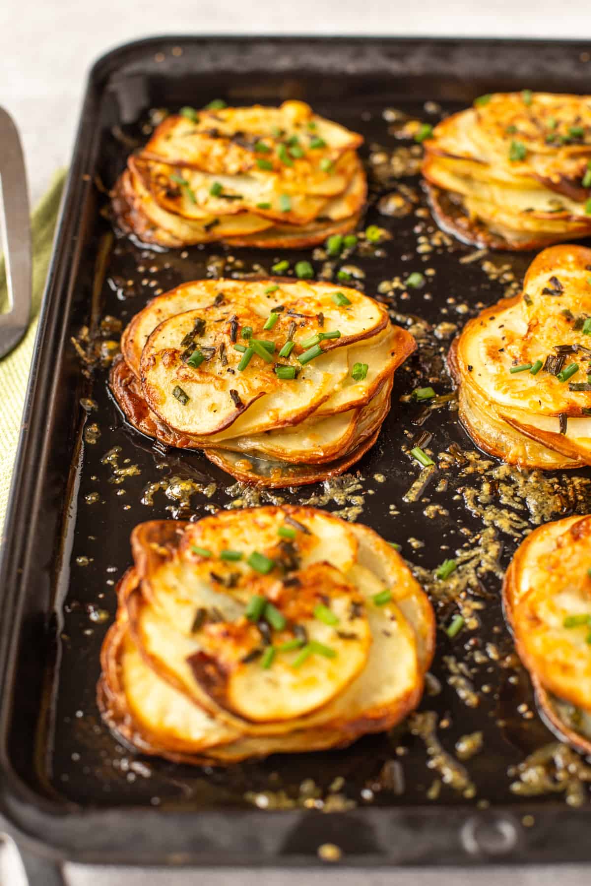 Small stacks of Easy Cheesy Potatoes Anna on a baking sheet.