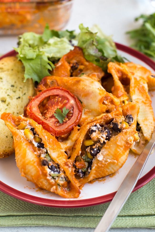 Portion of enchilada stuffed pasta shells on a plate with salad