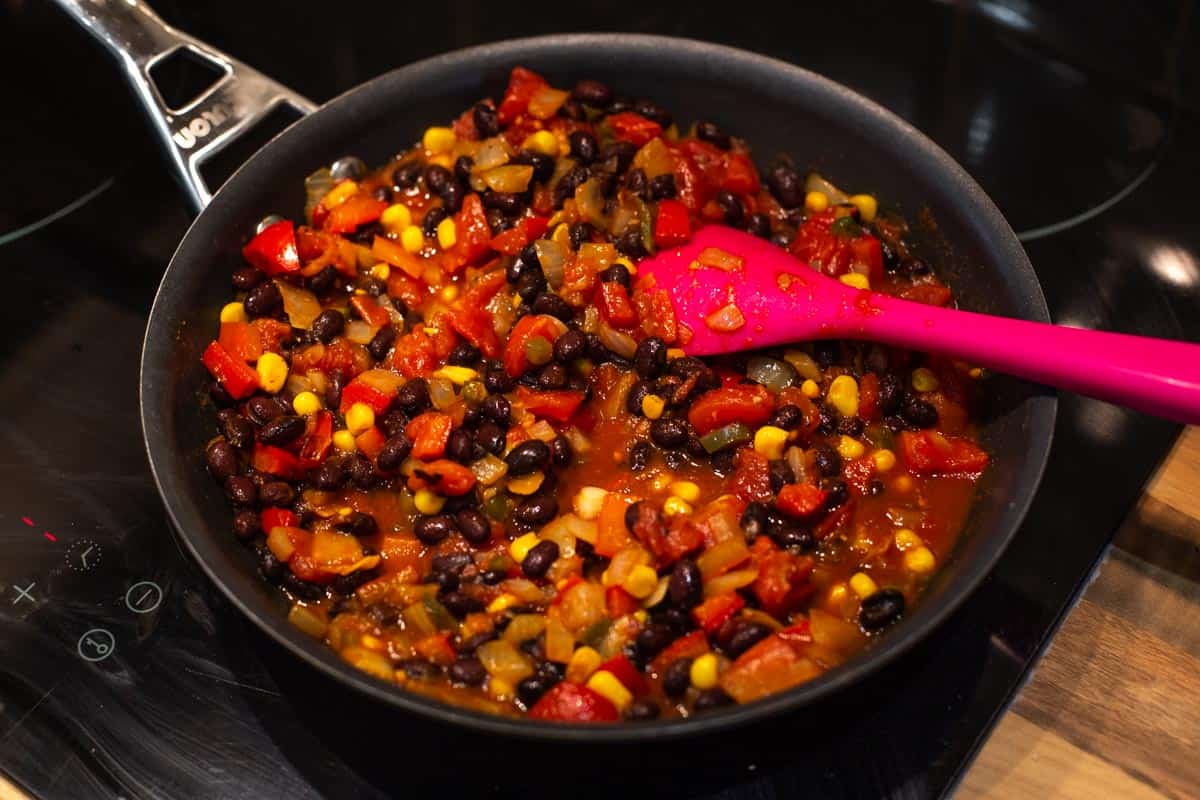 Tomato and bean chilli cooking in a frying pan.
