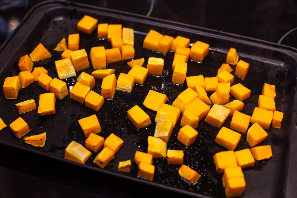 Diced roasted butternut squash on a baking tray.