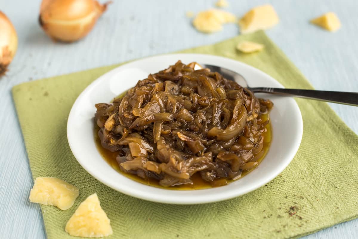 A plateful of caramelised onions on a white plate with chunks of mature cheddar.