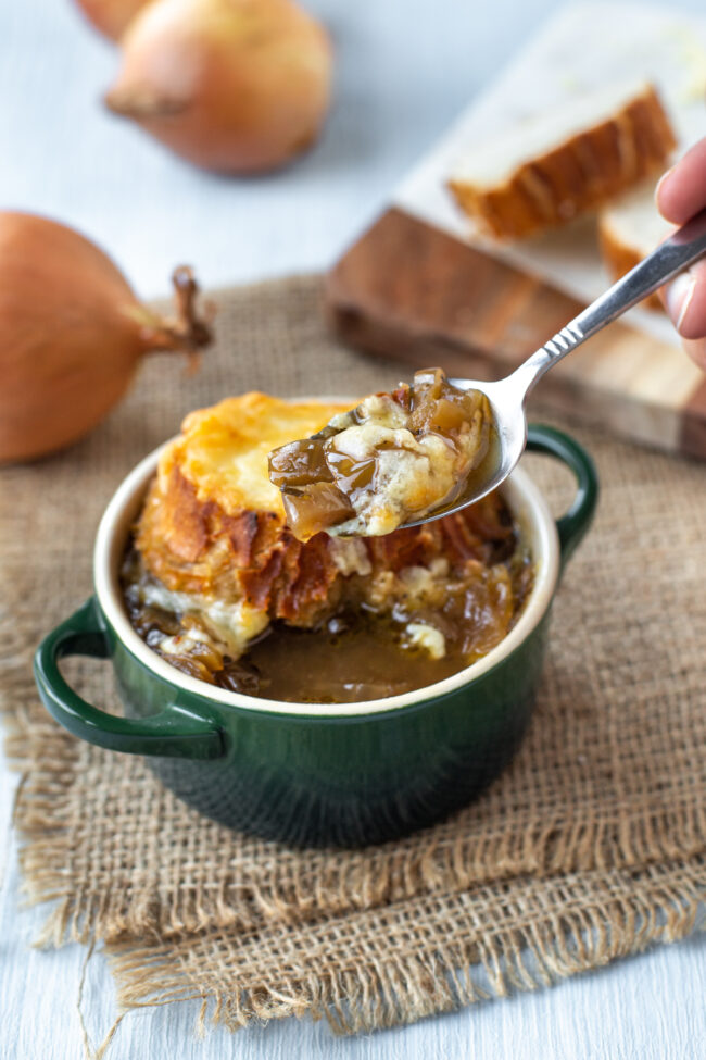 A spoon taking a scoop of French onion soup.