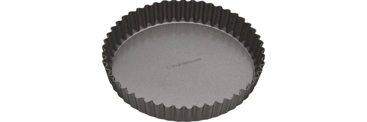 A metal loose-bottomed tart tin on a white background.