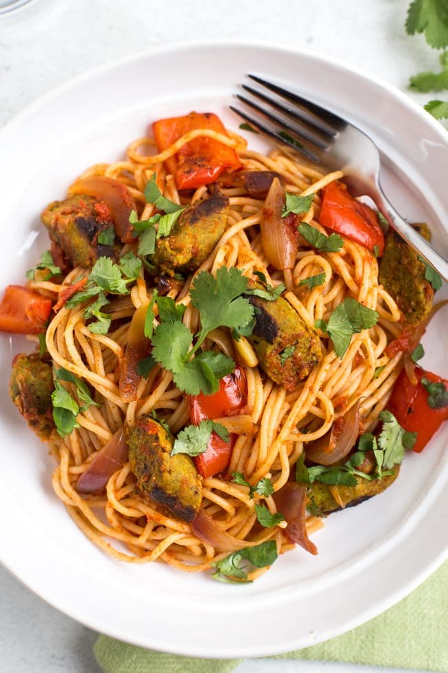 Portion of vegan curried sausage pasta in a bowl topped with cilantro