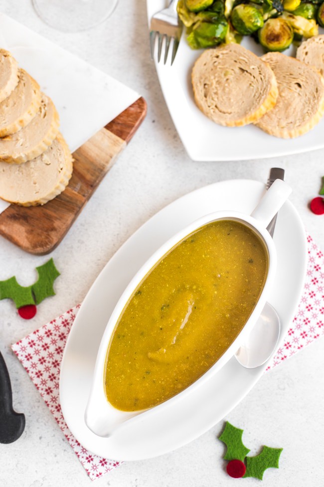 Vegan vegetable gravy in a gravy boat alongside a vegetarian Christmas feast