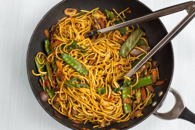 Stir-fried vegetables and noodles in a wok.